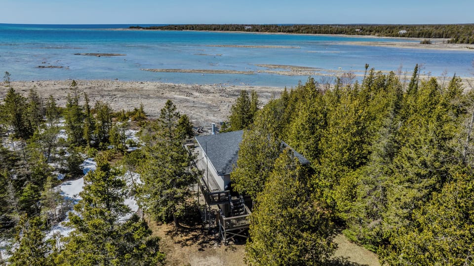 Private cottage retreat offering stunning panoramic views of turquoise waters and rocky shores, perfect for an unforgettable lakeside getaway.
