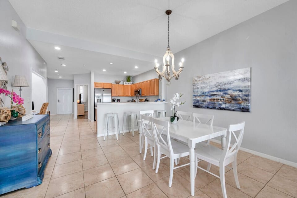 Open dining area w/ sleek white table, modern lighting & a seamless flow to the kitchen.