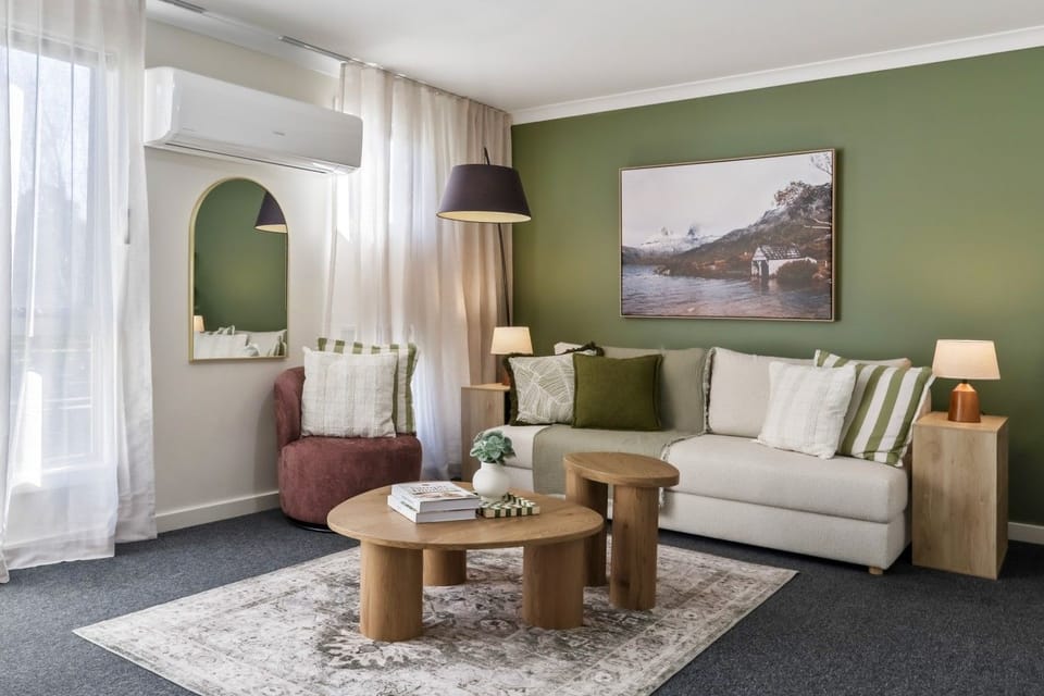 Bright living area with a large, comfortable queen sofa bed and stylish green feature wall