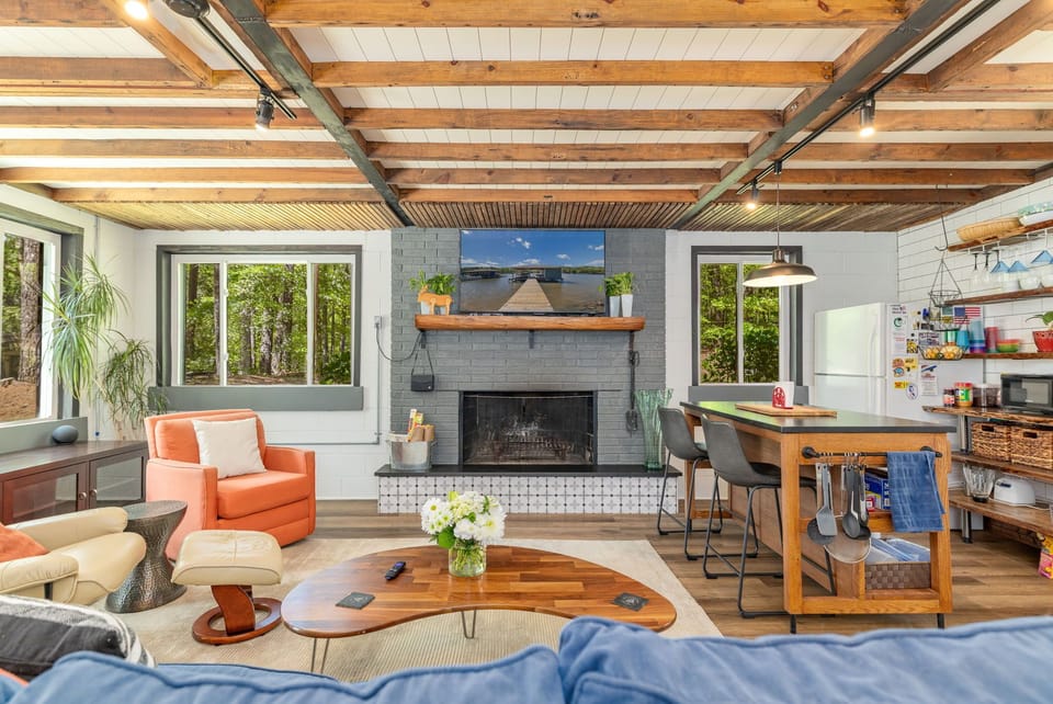 Living room with two chairs and couch that seats 3, wood burning fireplace, TV