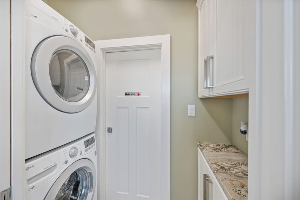 Your private laundry room features stacked washer and dryer units, granite countertop for folding, and ample cabinet storage for supplies.