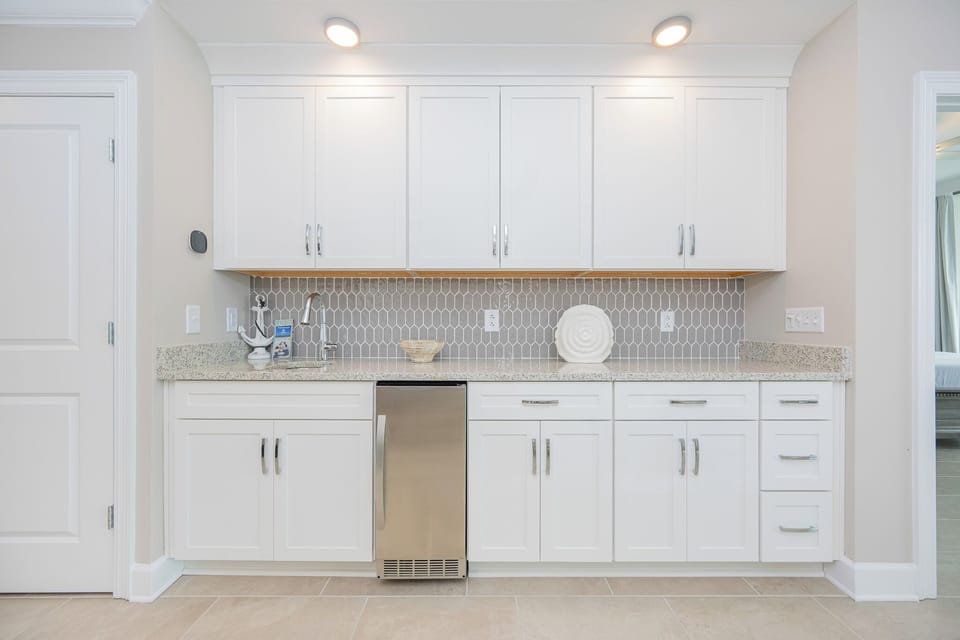 Prepare drinks at this sleek wet bar featuring stylish countertops and decorative accents