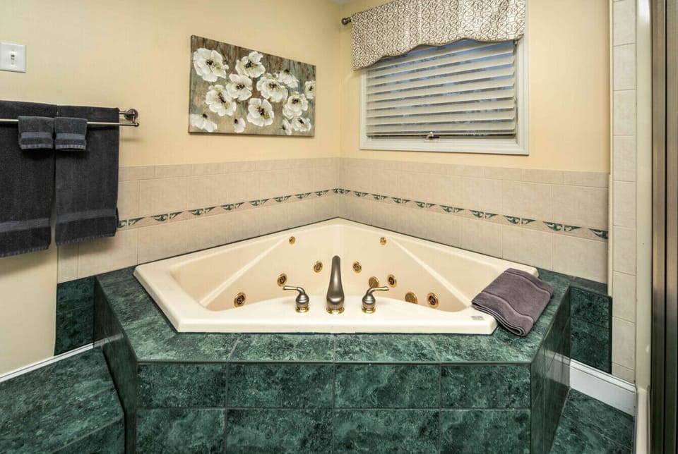 Full Bathroom 1 (Jacuzzi Tub) | Luxurious corner jacuzzi tub with jets, decorative tile accents, and spa-like ambiance