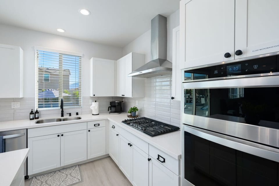 Spacious kitchen featuring a double oven, gas range, Keurig machine, and a large sink overlooking the pool area.