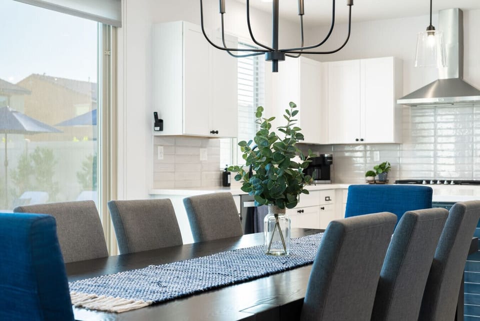 Modern dining space with a large table, elegant chandelier, full place settings for ten, and views into the open kitchen—ideal for family dinners and entertaining.