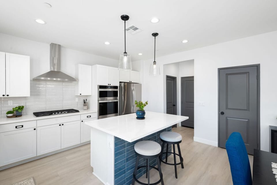 Fully equipped kitchen with quartz countertops, island seating, double ovens, gas range, and modern lighting—perfect for group meals or casual breakfasts.