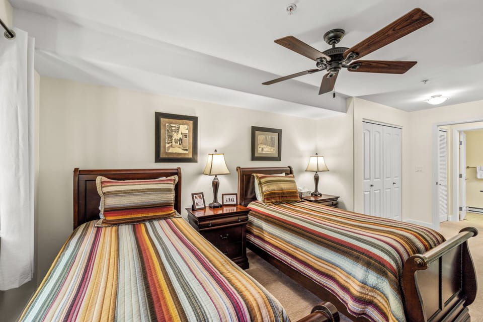 Twin bedroom with ceiling fan and streaming TV