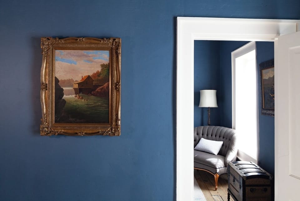 Rich blue walls create an inviting atmosphere in this thoughtfully designed space, where classic artwork and elegant furnishings blend seamlessly with modern comfort for your memorable stay.