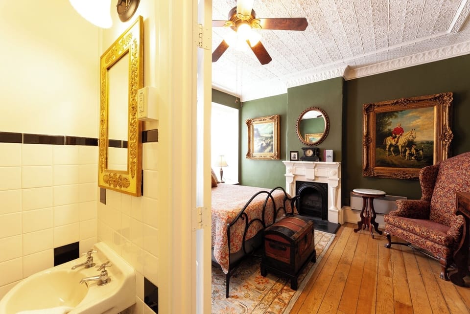 Step into a classic room where antique charm meets comfort—ornate mirrors, a fireplace, rich hardwood floors, and timeless décor create a warm, inviting retreat just for you.
