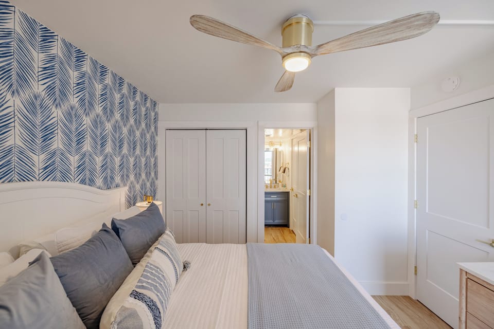 Cozy bedroom with patterned accent wall and ceiling fan