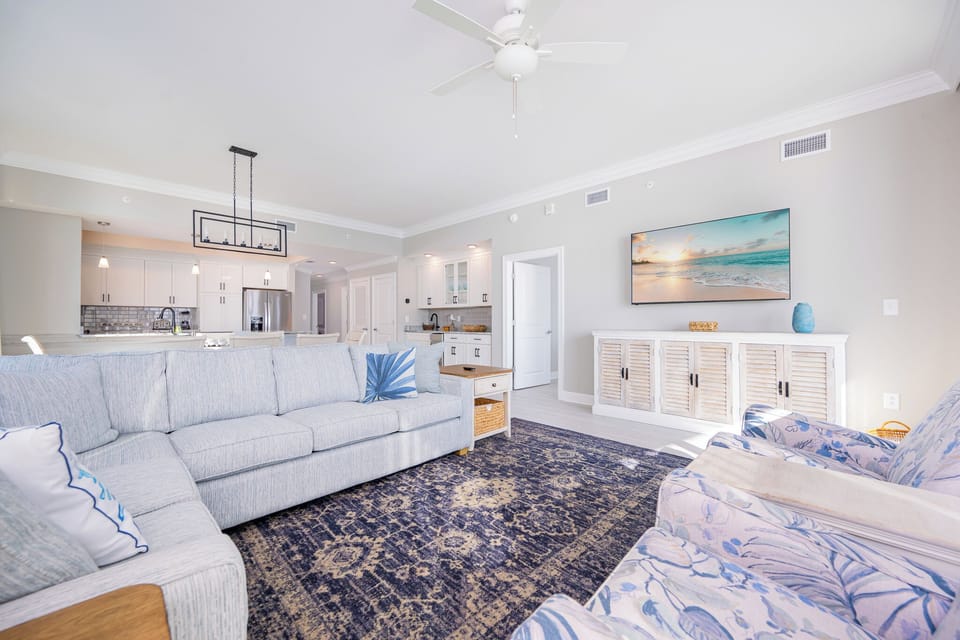 Relax in the inviting living area with plush seating, a large TV, and easy access to the stylish kitchen