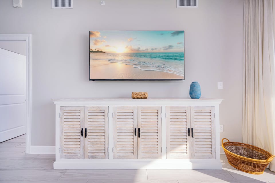 Stylish living space with a large TV, coastal entertainment cabinet, and inviting decor that enhances your comfort