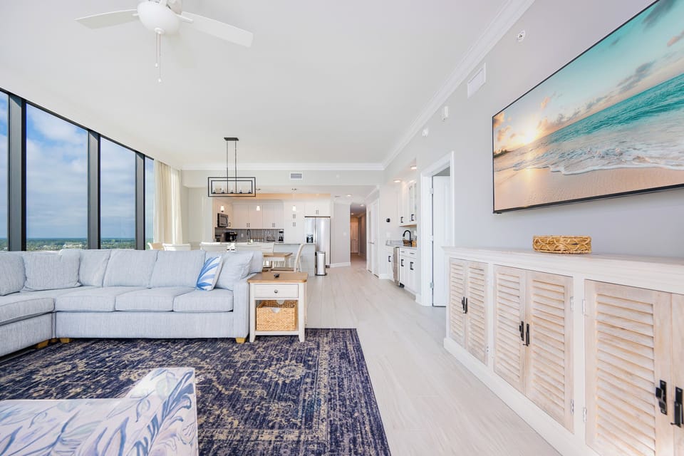 Relax in the spacious living area, featuring a sectional sofa, large TV, and beautiful beachfront views