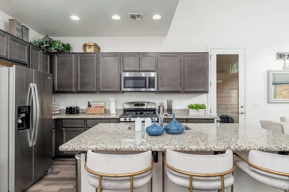 Your fully-equipped kitchen awaits, featuring granite countertops, modern appliances, and island seating—perfect for preparing meals and gathering over morning coffee.