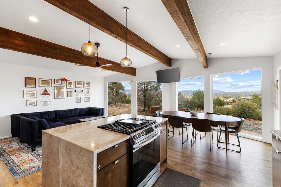 - Open kitchen and living room with wide windows and sweeping mountain views - Spacious island and dining area designed for group gatherings - Warm wood beams add charm to this bright Arizona getaway