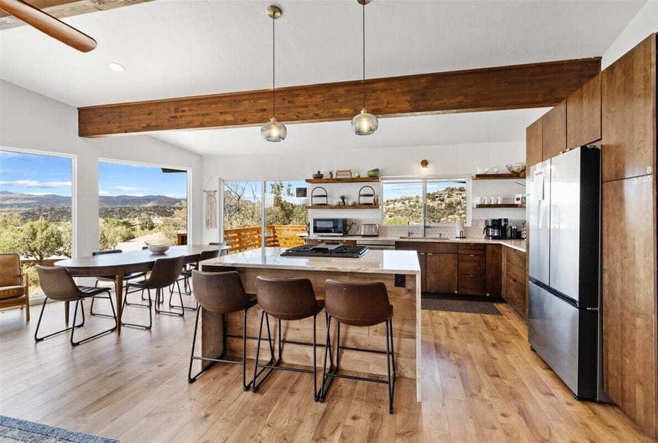 - Bright open kitchen with panoramic mountain views all around - Large island seating blends comfort with modern cooking space - Dining area opens to fresh air and scenic sunshine under warm sunshines