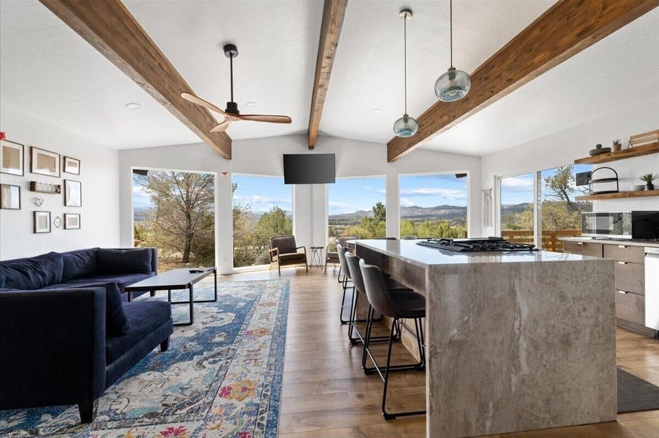 - Vibrant living area with picture windows framing desert scenery - Comfortable sectional and stylish rug create a warm atmosphere - Open design flows seamlessly into the bright kitchen space viewsday