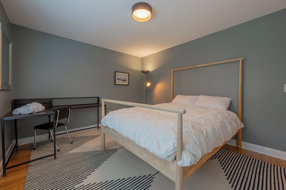 Quiet guest room with queen bed, desk space, and soft, relaxing tones.