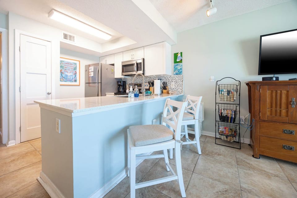 The kitchen features sleek stainless appliances, granite countertops, and a cozy seating area for casual dining