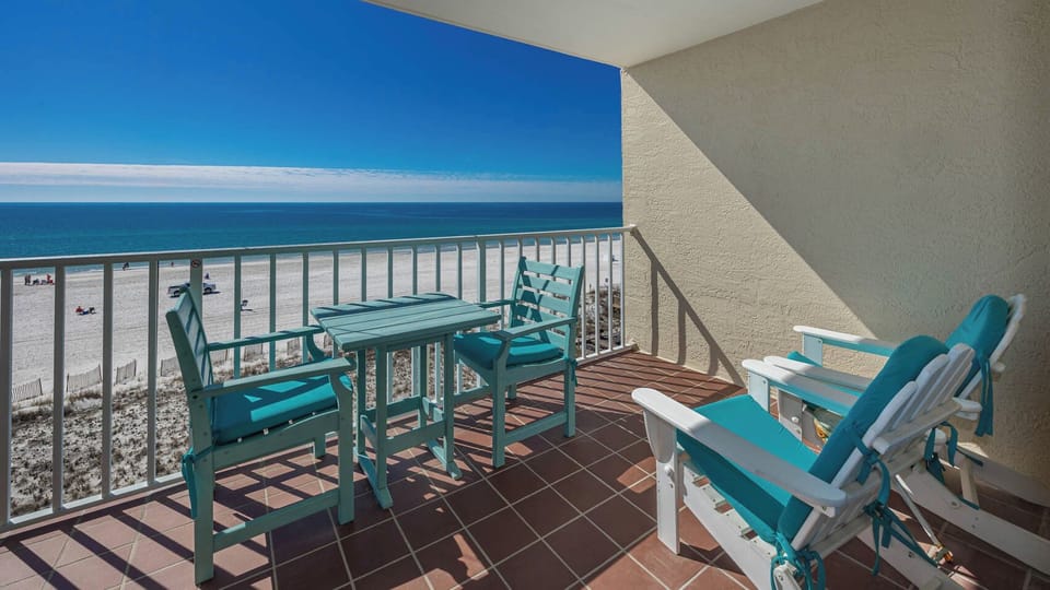 Enjoy breathtaking beachfront views from this balcony, featuring turquoise chairs and a table for relaxation