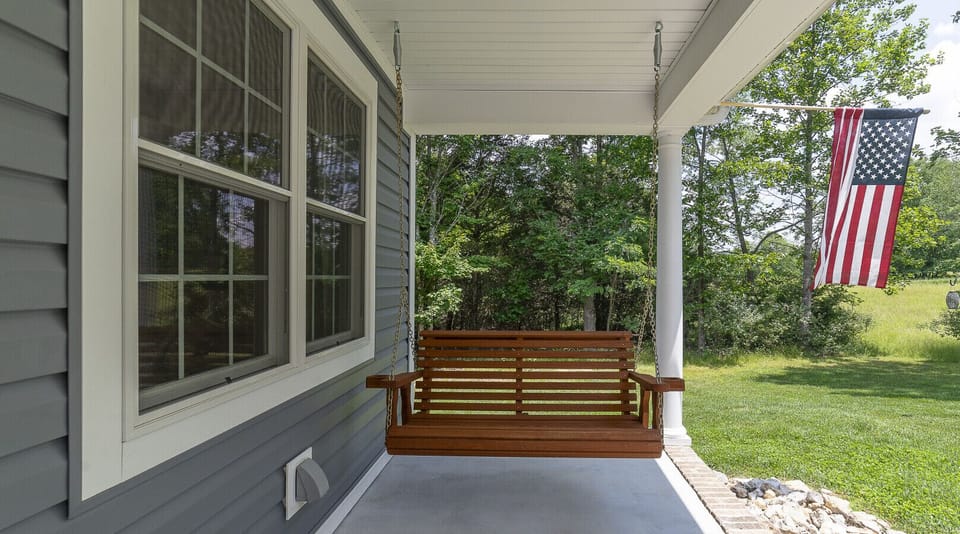 Front porch features a bench swing and view to the neighboring property.