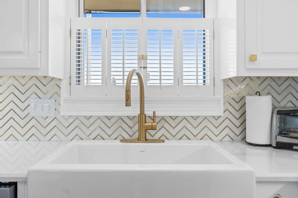 An upgraded tile backsplash adds a touch of elegance and coastal flair, complementing the clean lines and contemporary finishes throughout.