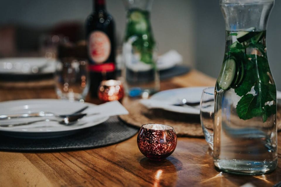 A beautifully set dining table in the rancho featuring mint and cucumber-infused water, candlelight, and elegant table settings—guests can easily recreate this refreshing touch to elevate their villa experience.