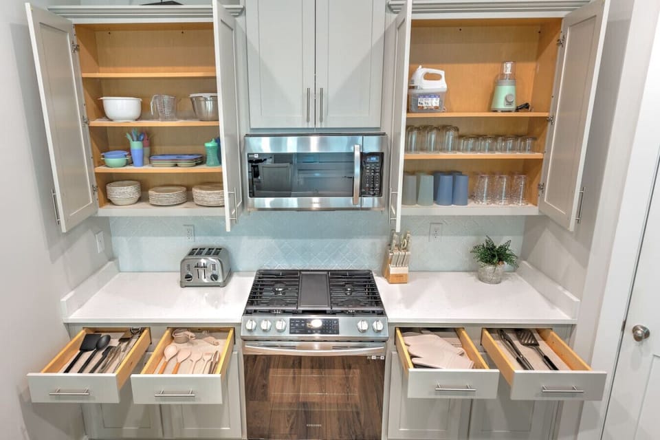This kitchen is seriously set up for success with its smart drawer organization, beautiful white cabinetry, and that stainless steel gas range just waiting for you to whip up something delicious.