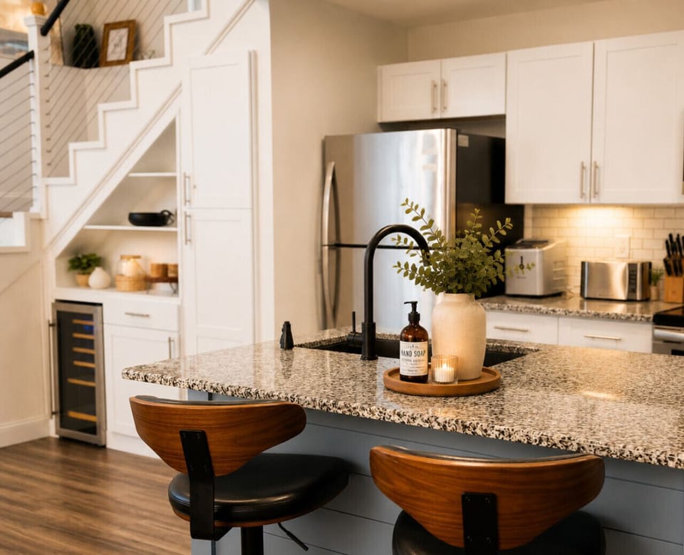 Cook and gather in this stylish modern lakehouse kitchen featuring granite countertops, stainless steel appliances, cozy seating, and upscale amenities perfect for family getaways and extended stays.