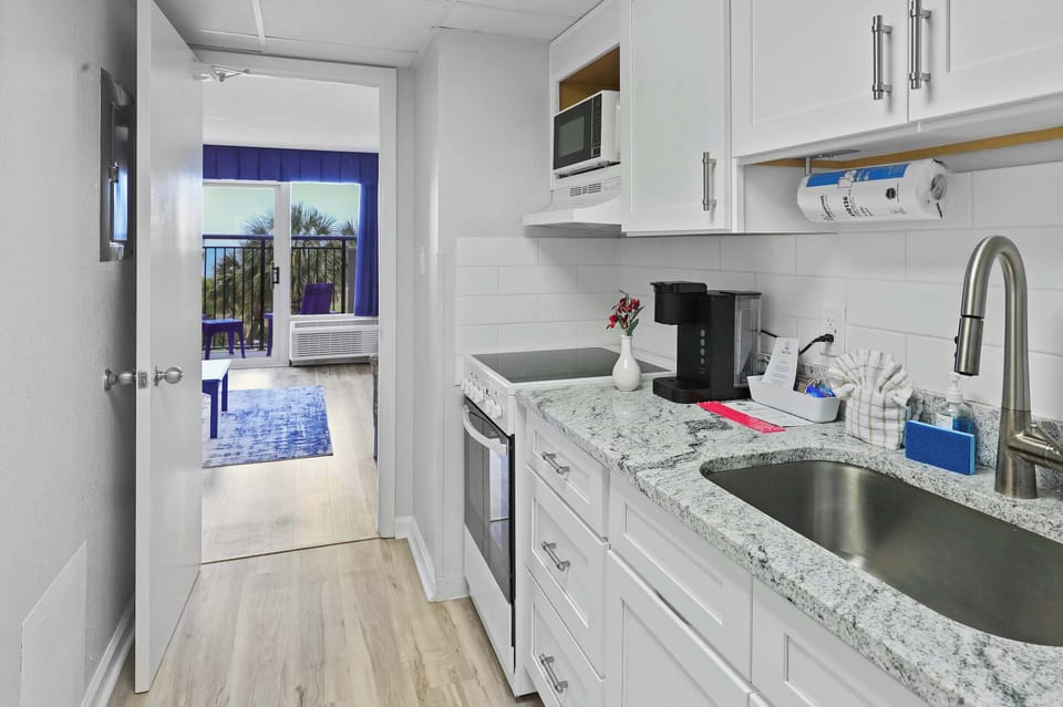 Whip up breakfast with an ocean breeze just steps away! This sleek, fully stocked kitchen has everything you need—and the view from the doorway? Just icing on the cake. 