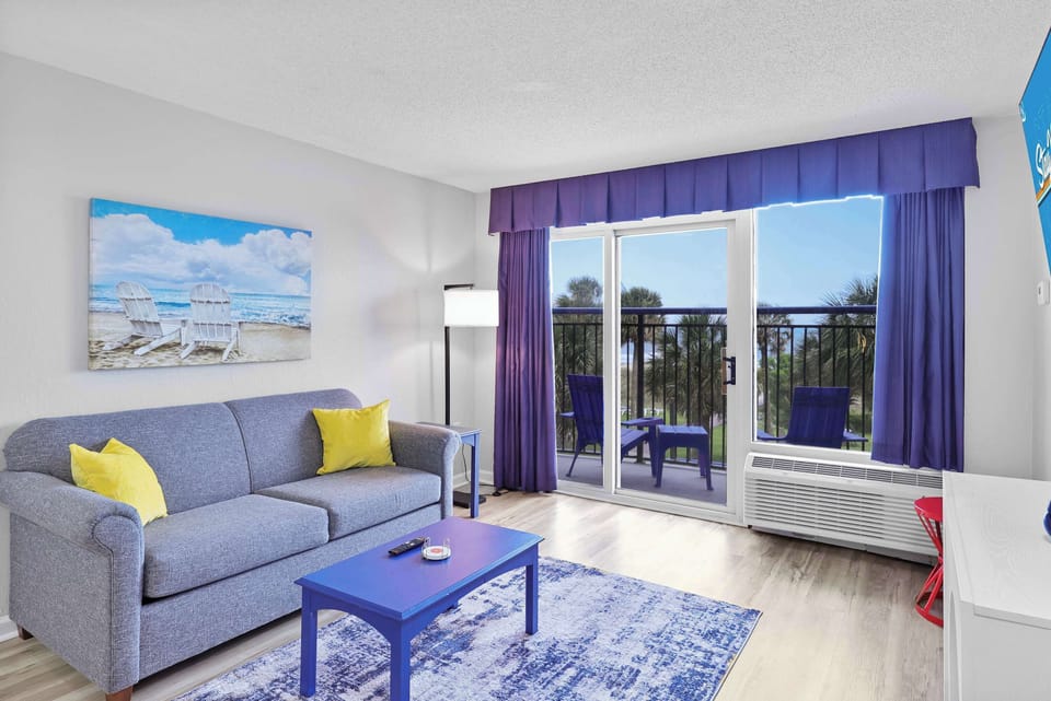 Wake up to palm trees and ocean views in this vibrant, coastal-chic living room. Slide open the doors, sip your morning coffee on the balcony, and let the sea breeze set the mood. 
