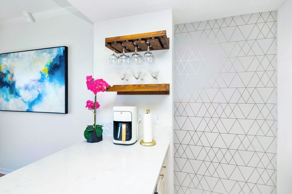 Your stylish wet bar awaits with geometric tile, floating shelves for glassware, and fresh coffee ready to brew.