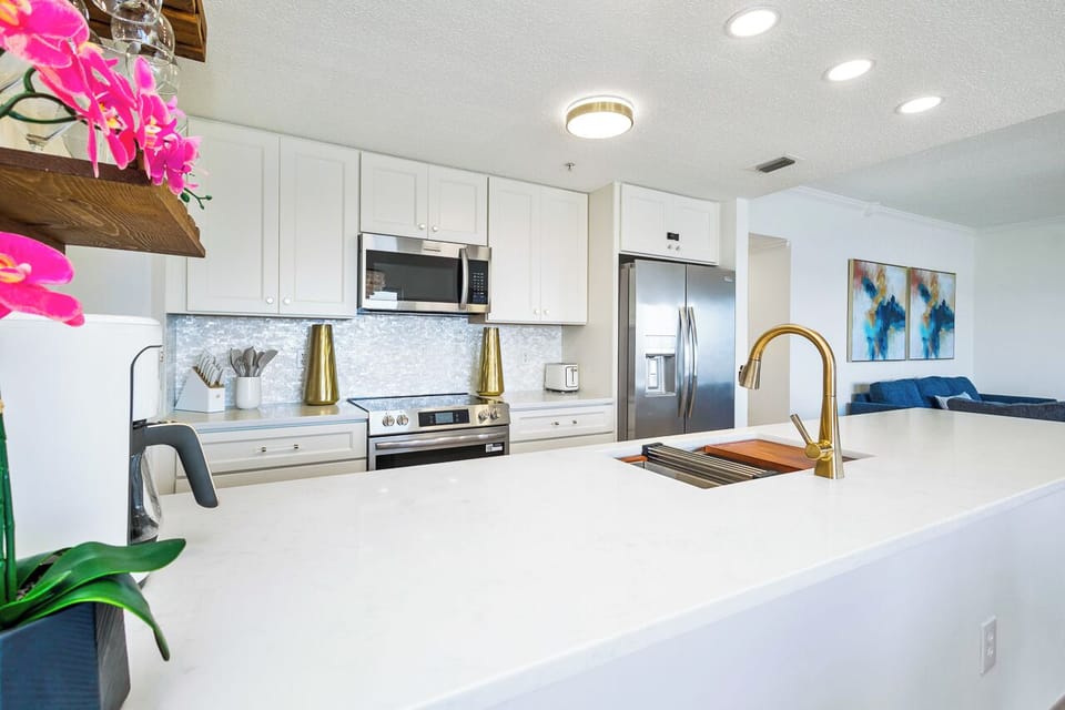 Cook with ease in this bright kitchen featuring gleaming countertops, modern appliances, and elegant gold fixtures.