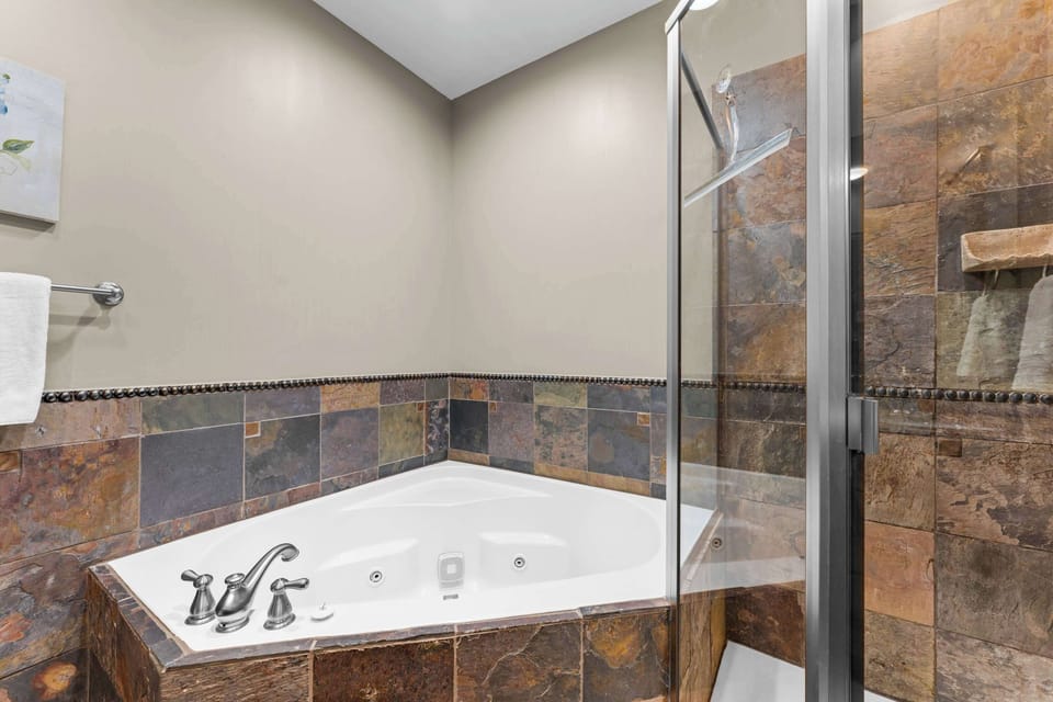 This king ensuite includes a double vanity, shower, & luxurious soaking tub