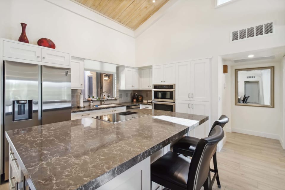 Kitchen with sleek marble island, double ovens, and vaulted ceilings.