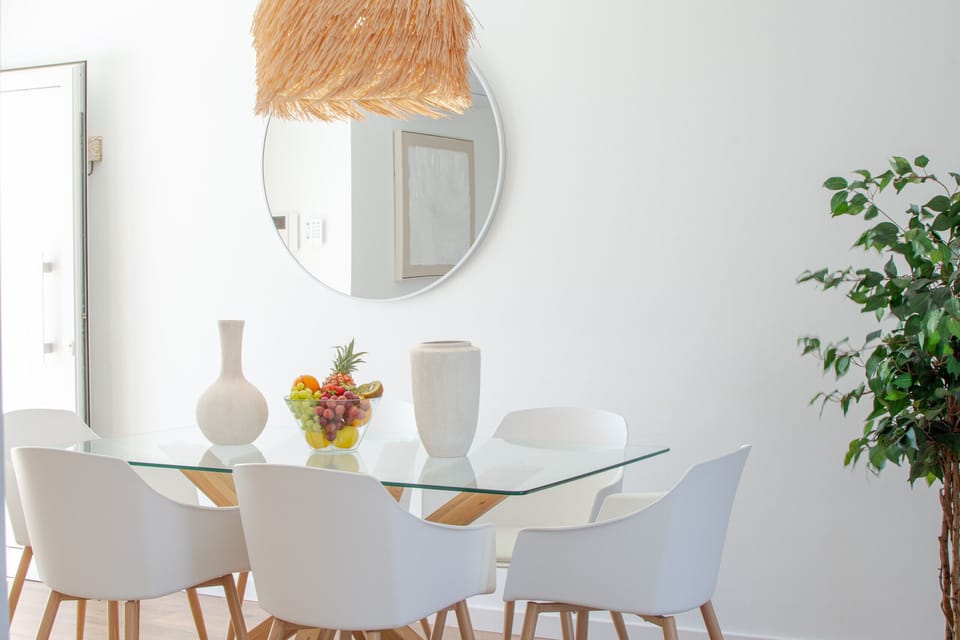 Elegant dining room with round glass table and designer chairs.