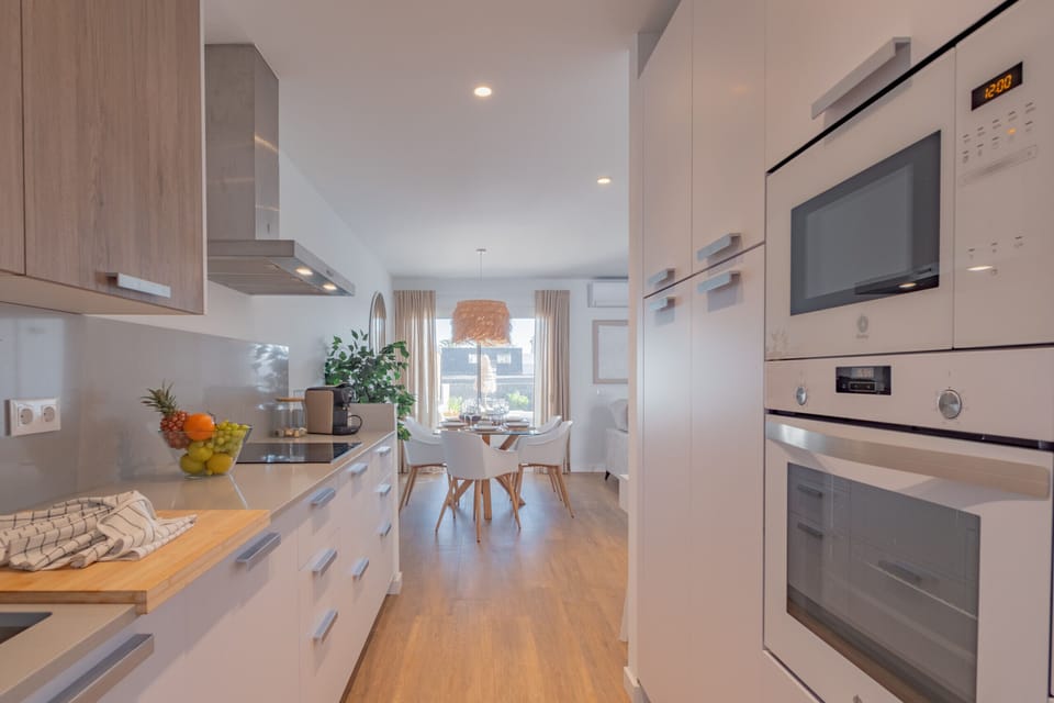 Modern equipped kitchen with white and wood finishes.