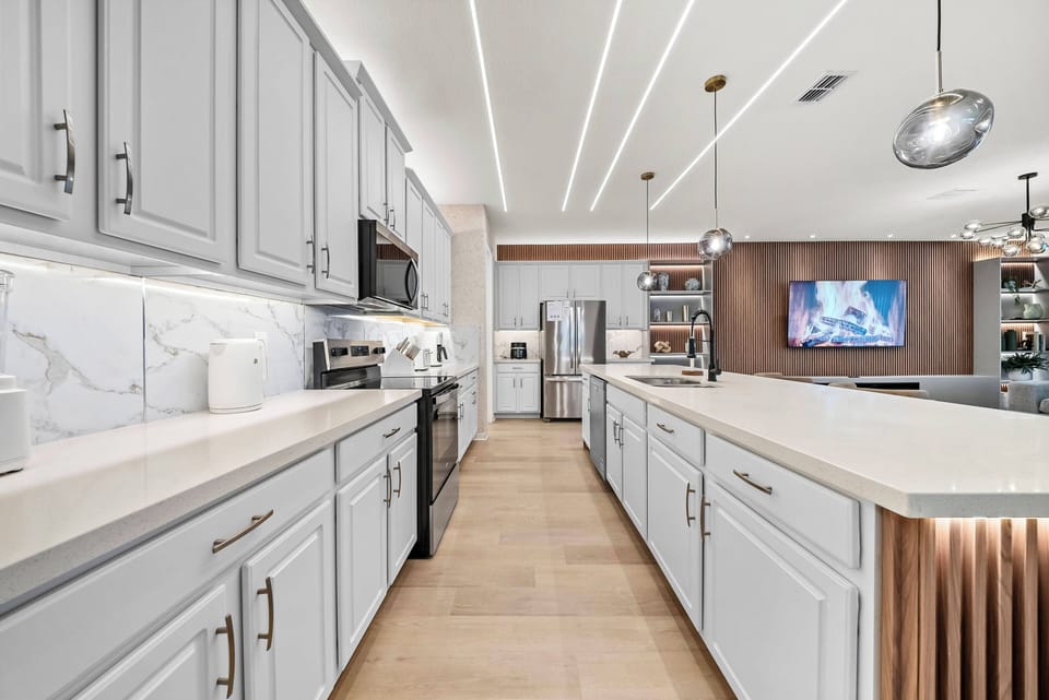 Enjoy a stylish kitchen featuring soft gray cabinetry and stunning marble backsplashes. The spacious layout inspires culinary creativity, while contemporary lighting adds warmth, making it perfect for gatherings.
