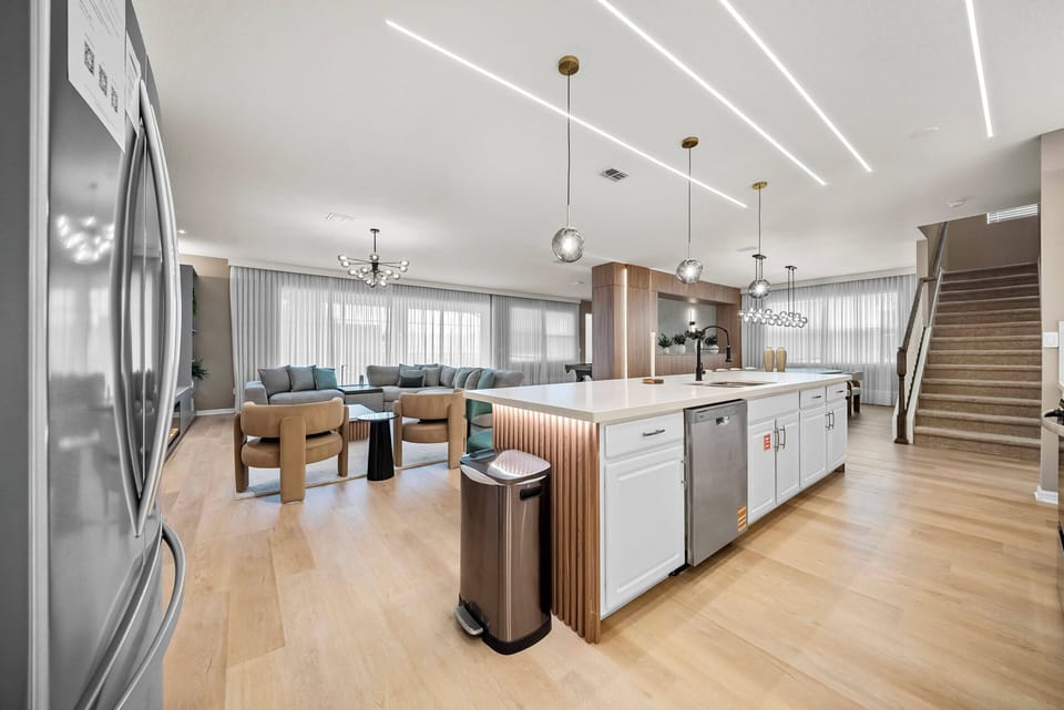 Welcome to this inviting kitchen and living area, boasting sleek cabinetry and a spacious island ideal for entertaining. Enjoy the warmth of natural wood flooring and abundant light from large windows, complemented by modern.