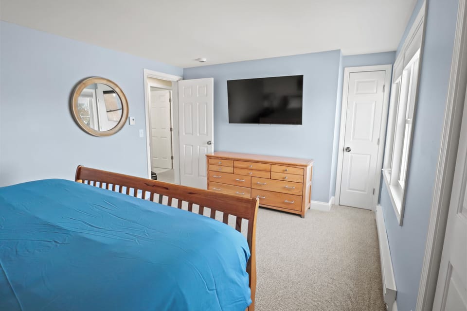 Master bedroom with King bed, 55" smart TV, A/C, fan, and ample storage.