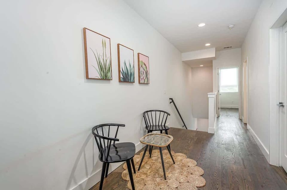 Second-Floor Landing beckons you to relax in two cozy chairs around a charming table beneath vibrant wall art.