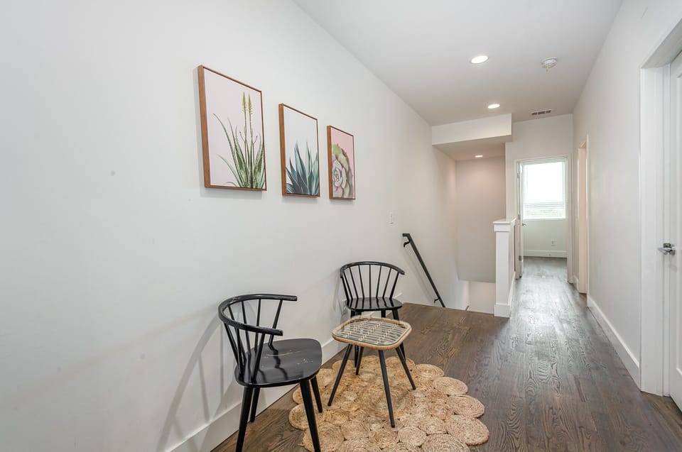 Unit 1: Second-Floor Landing beckons you to relax in two cozy chairs around a charming table beneath vibrant wall art.