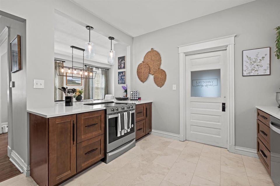 Cook with ease in this fully equipped kitchen featuring quartz countertops, modern pendant lighting, and direct access to the laundry room for long-stay convenience.