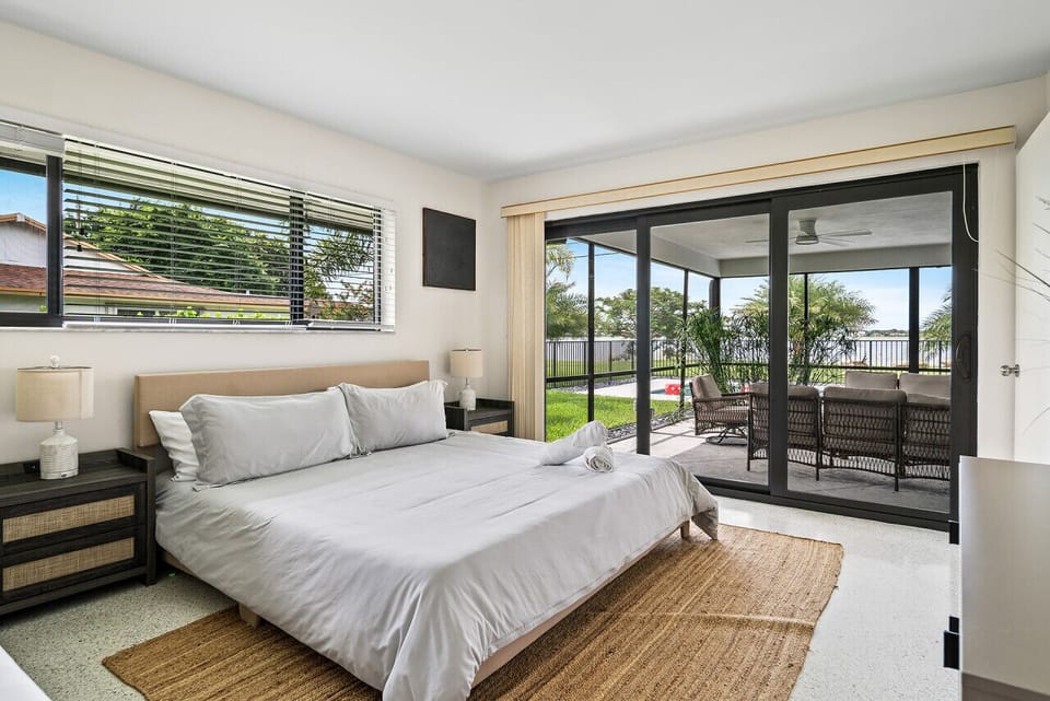 Serene bedroom offers a comfortable king-sized bed and large sliding glass doors leading to a balcony with water views.
