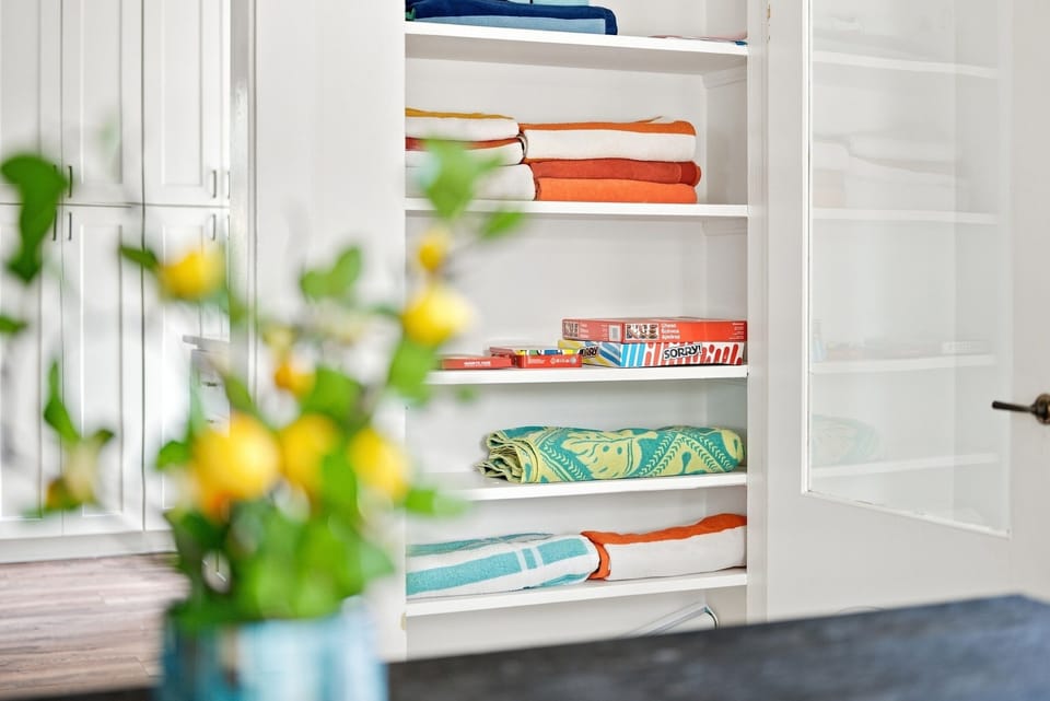 Organized linen closet stocked with colorful towels and family games.
