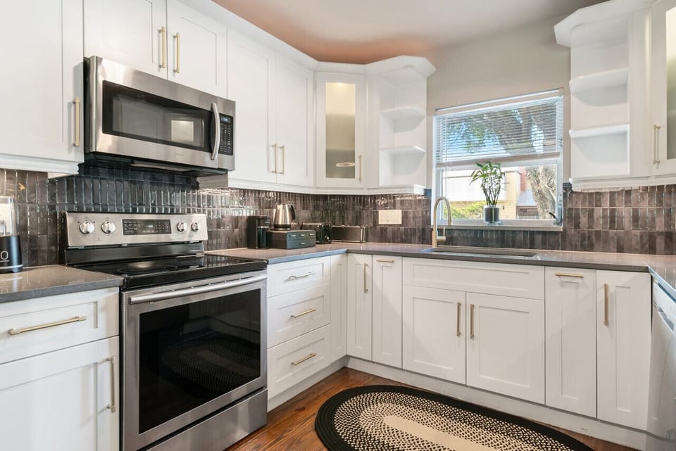 Cook with joy in this bright, modern kitchen. White cabinets and sleek appliances make meal prep a delight. Natural light fills this inviting space.

