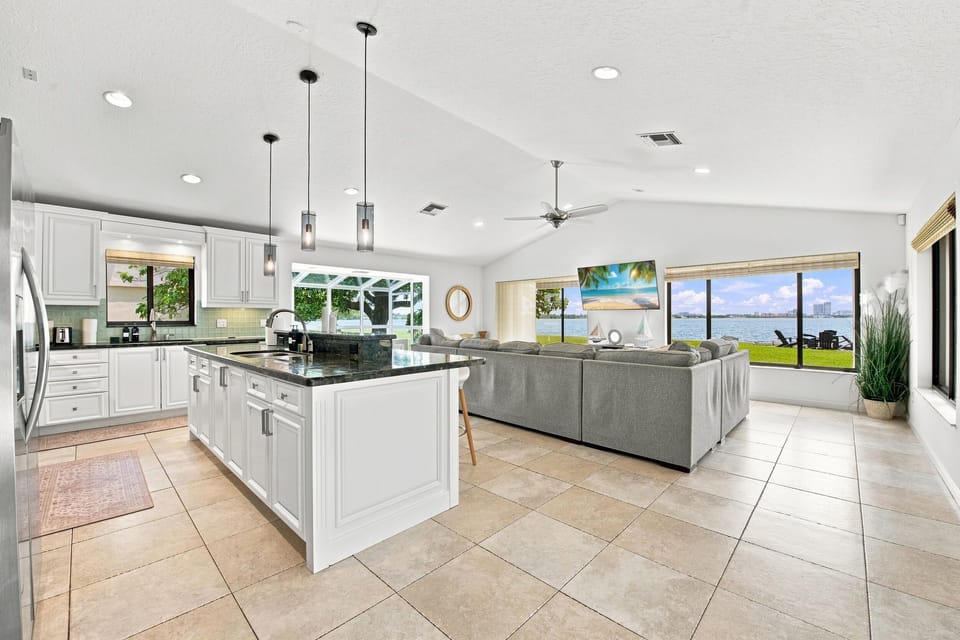 Bright kitchen island opening onto the living room with waterfront views.