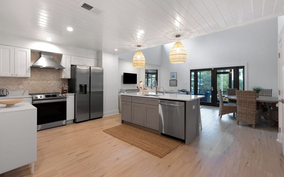 Gather with loved ones in this stunning open-concept kitchen featuring warm wood floors, pendant lighting, and stainless steel appliances.