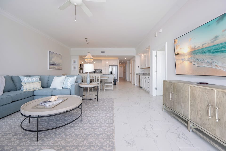 Relax in the spacious living area, featuring a plush sectional, elegant decor, and a large TV