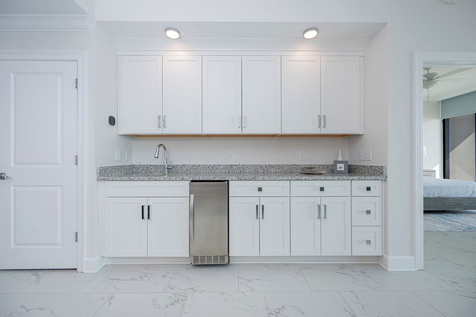 Pour a drink from the wet bar with elegant countertops and stylish light accents
